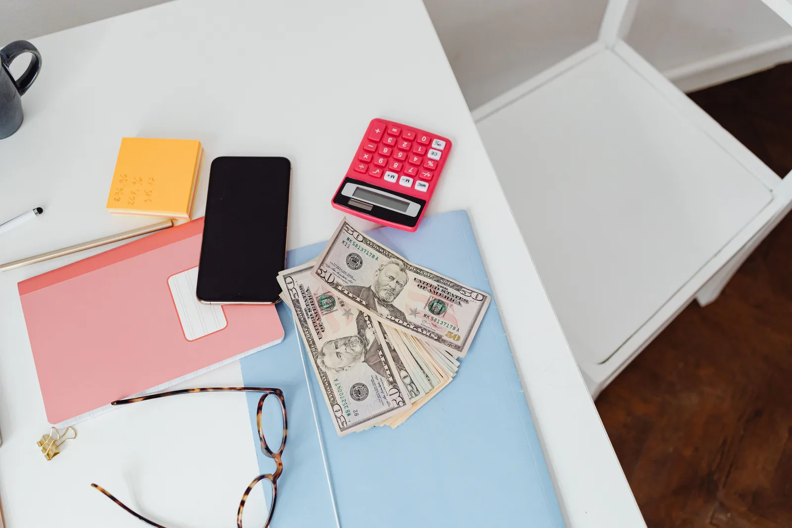 Overhead view of office desk with calculator, money, and glasses, depicting finance and budgeting. Airbnb and Vrbo host fees for Canadian hosts with a CAD 40,000 example