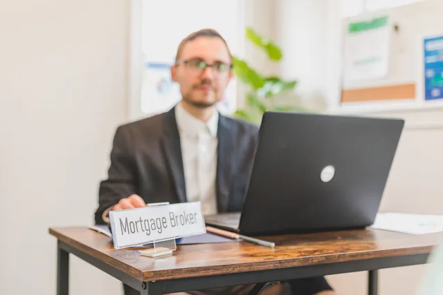 A mortgage broker working at a desk with a laptop in an office setting. How to Choose an STR Insurance Broker in the US and Ontario
