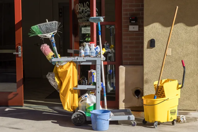 Cleaning supplies and tools outside a building entrance bathed in sunlight. How a short-term rental business hires people it can count on, explained