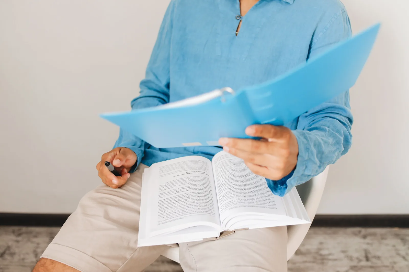 A man in casual attire reads and takes notes from a book indoors, adding insights. How to read a US city STR permit ordinance, using Nashville's code